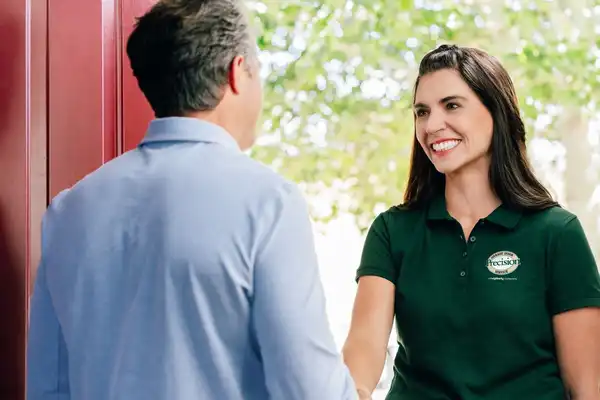 A Precision Garage Door service professional greeting a homeowner at the door.